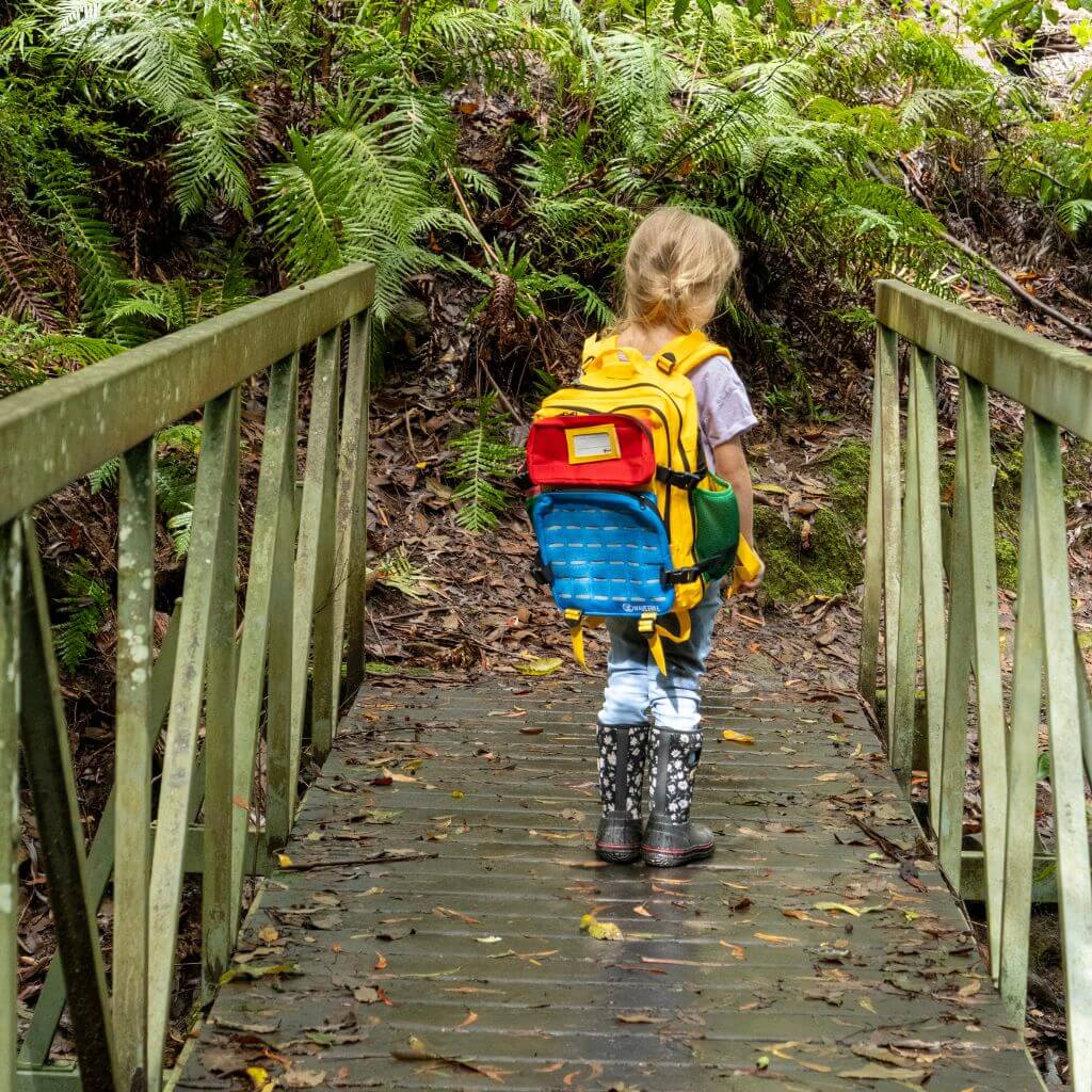 Girl hiking in the bush wearing colourful backpack and boots