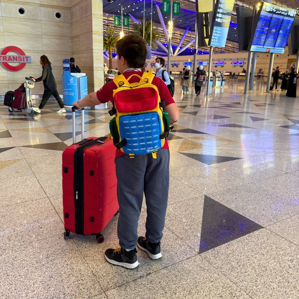 Boy travelling through airport wearing colourful backpack
