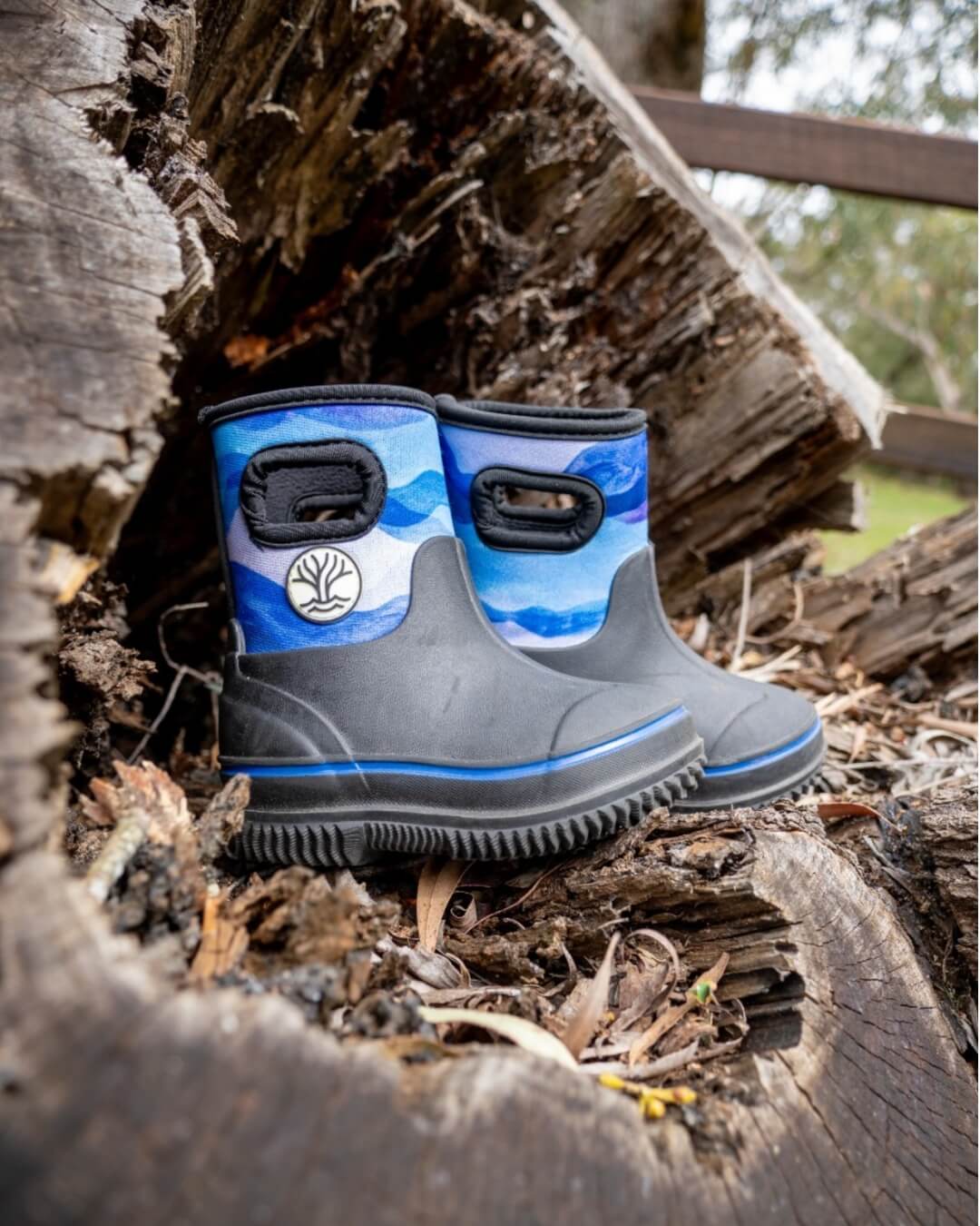Blue rain boots gumboots placed in a log