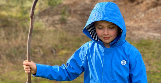 Boy in Blue raincoat holding a stick