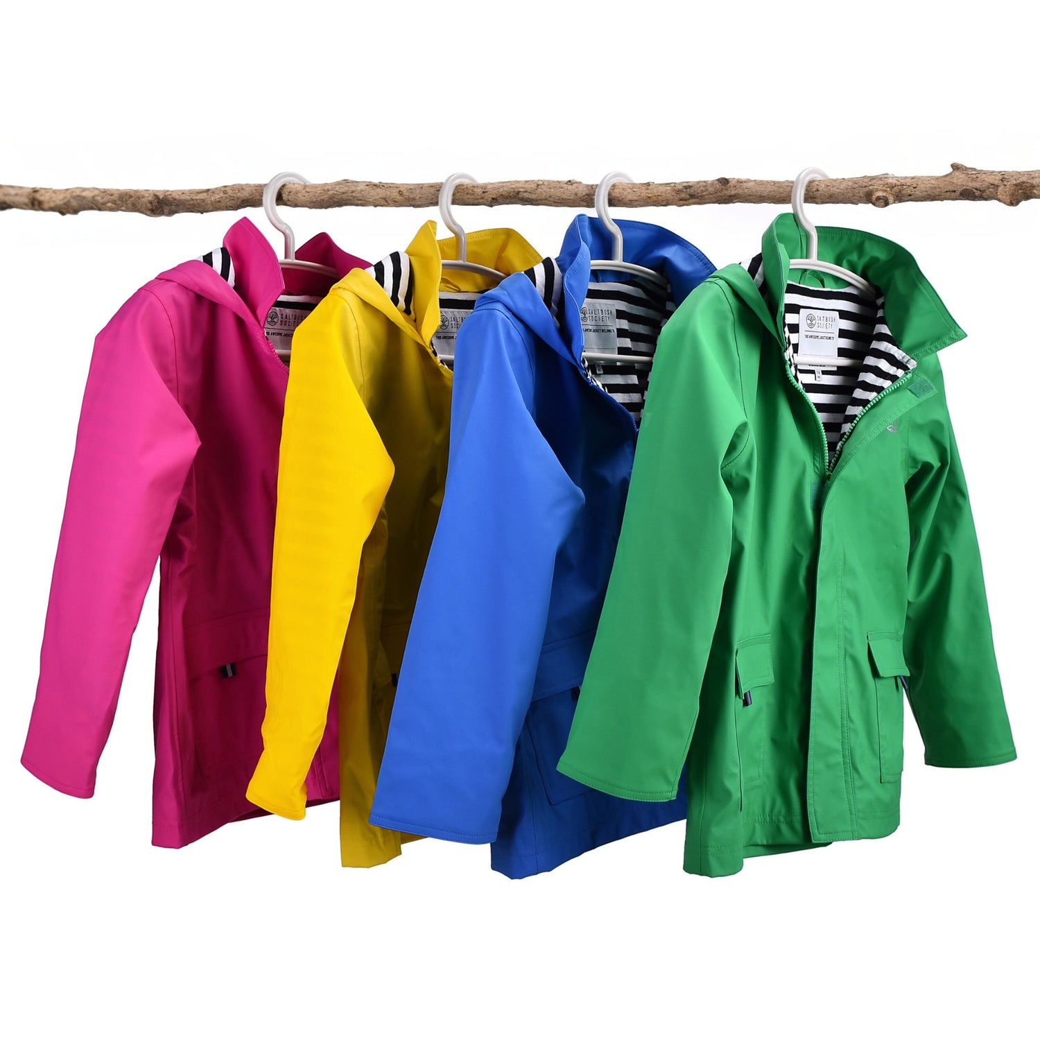 Classic Raincoats designed for kids. Four Raincoats hanging up on a tree branch in pink, yellow, blue and green